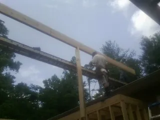Carpenter setting a ridge beam over a new addition frame — Ice Dam Removal by Roofing Brothers in Sinclair
