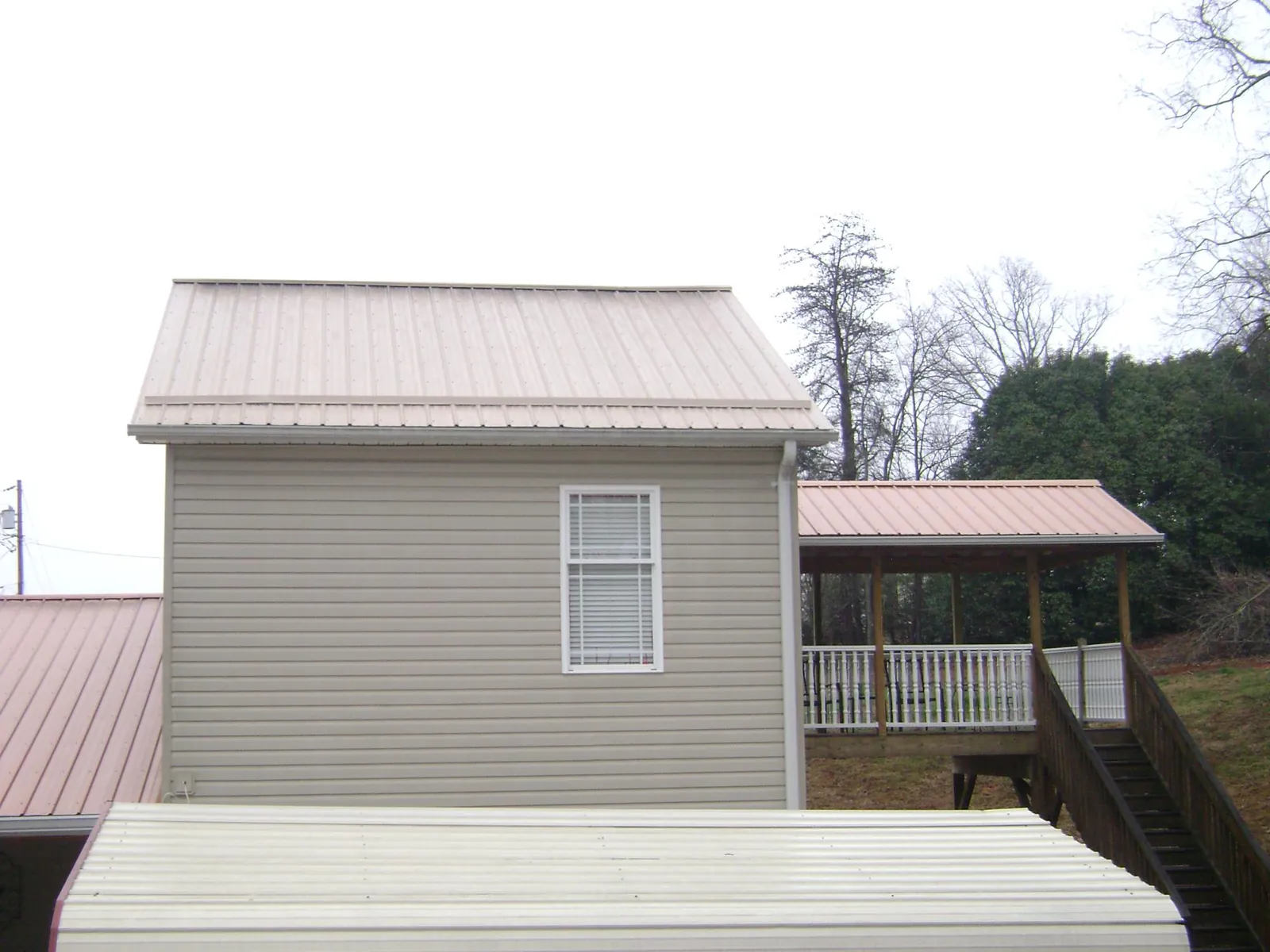 Tan metal roofs on a two story addition and attached porch, from a Roof Replacement job in Sinclair