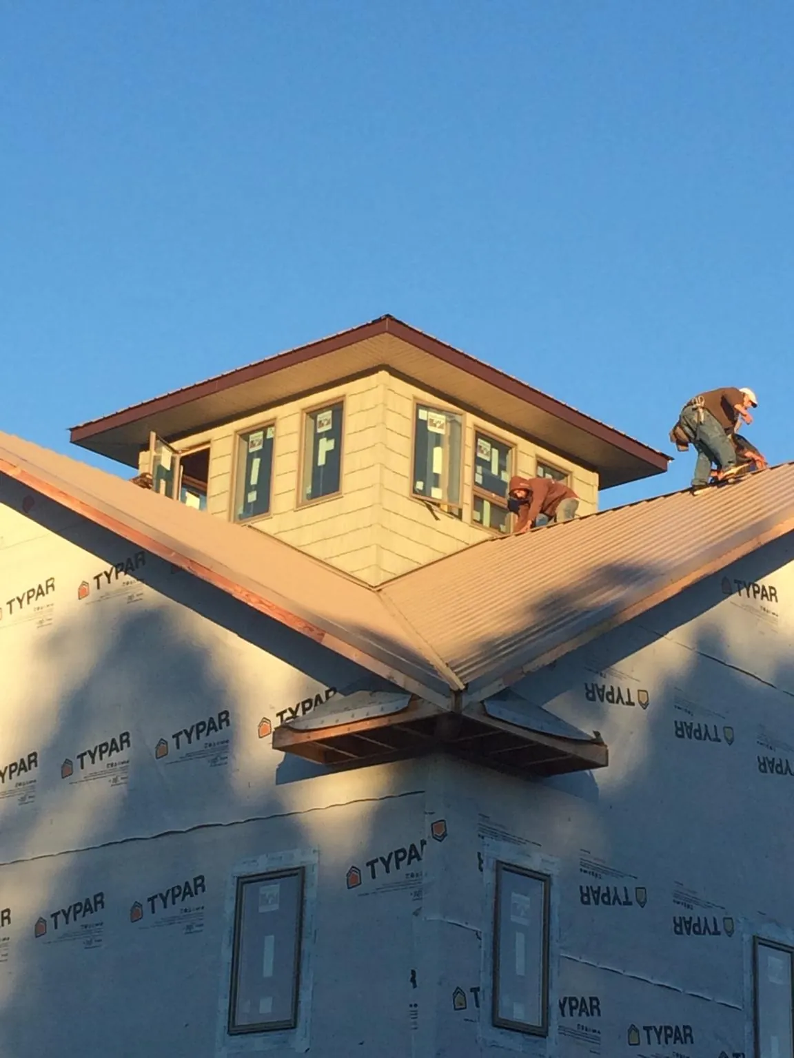 Roofers working around a rooftop cupola on a new metal roof at sunset — Roof Waterproofing in Sinclair by Roofing Brothers
